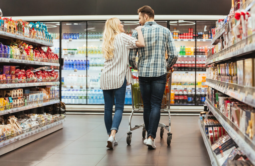 Back view of a smiling couple walking with a trolley at the supermarket